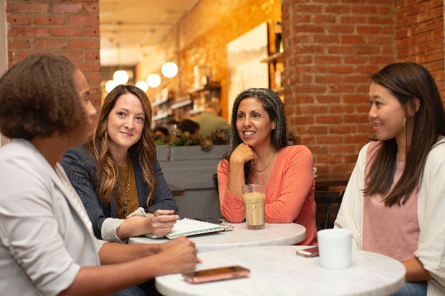 4 women talking over a table