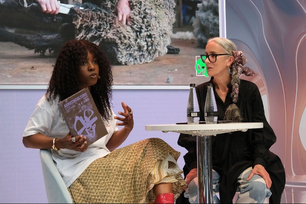 two people sat at table on stage having a talk