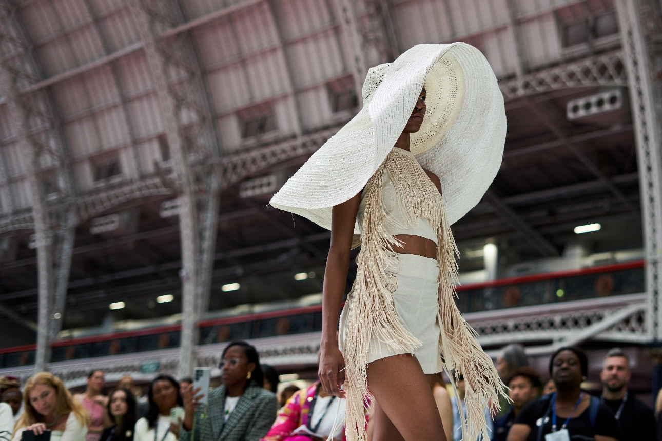 model in overside large white hate and skirt with long tassle over shoulders and outfit